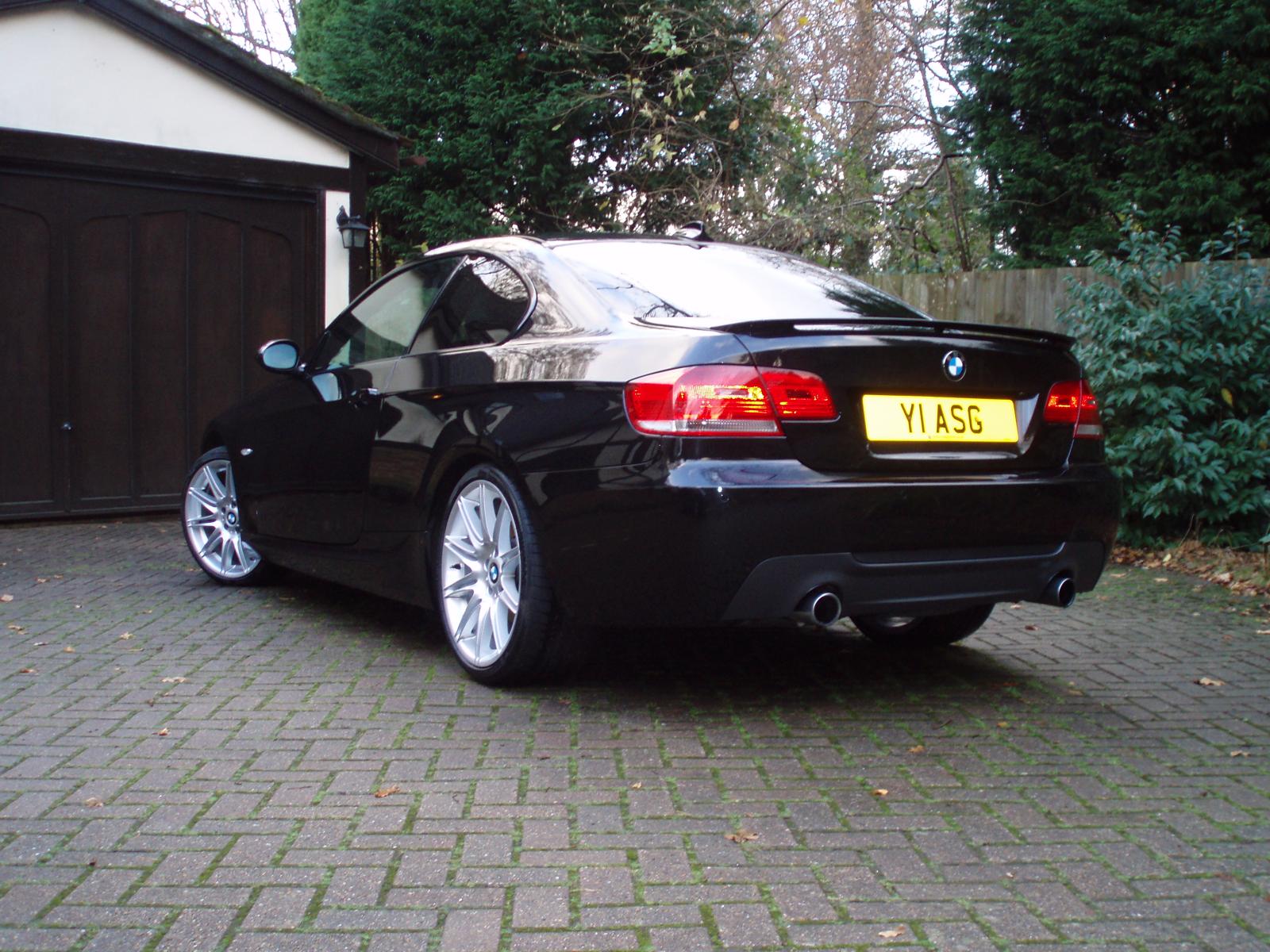 Black BMW E92 335i coupe viewed from the rear on a driveway